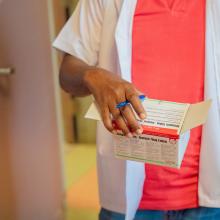 Carly Bonhomme, pharmacien, tends une boîte de médicaments à Bertha Joseph pour des patients suivant leur traitements contre le VIH.